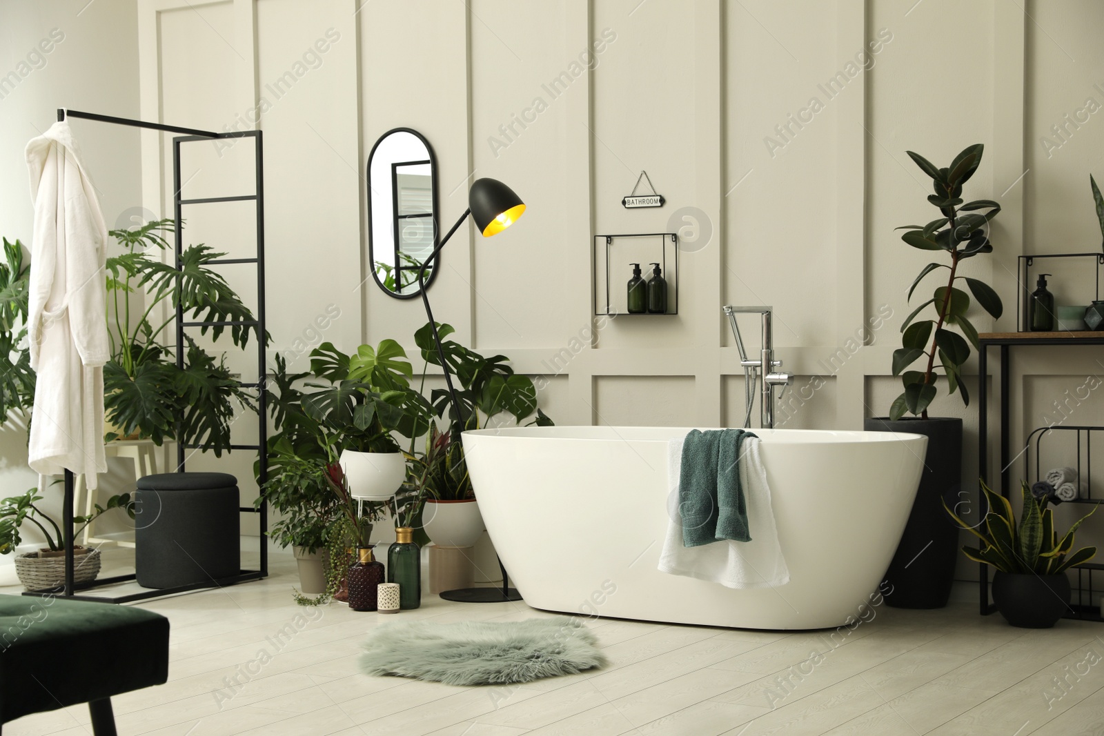 Photo of Stylish bathroom interior with modern tub and beautiful houseplants. Home design