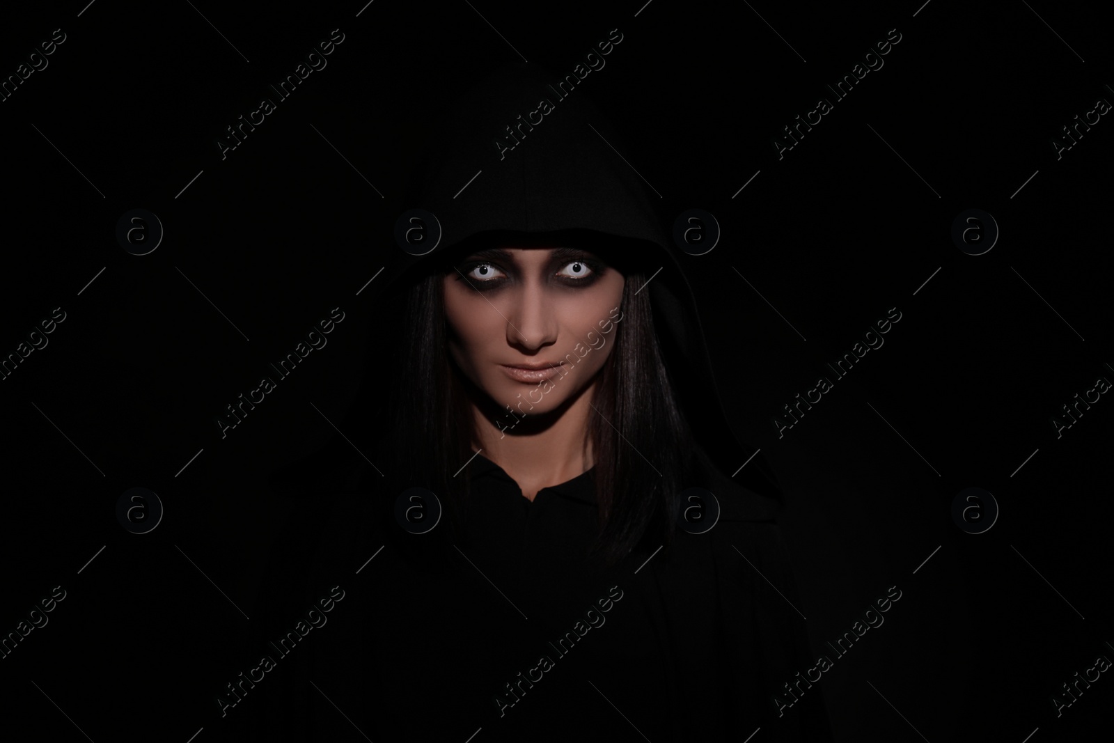 Photo of Mysterious witch with spooky eyes on black background