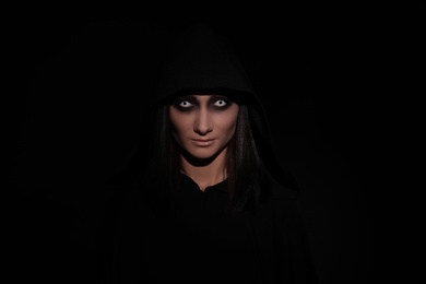 Photo of Mysterious witch with spooky eyes on black background