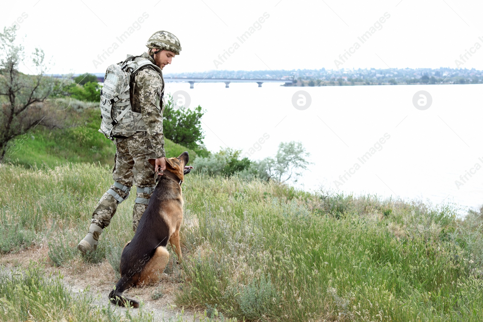 Photo of Man in military uniform with German shepherd dog outdoors