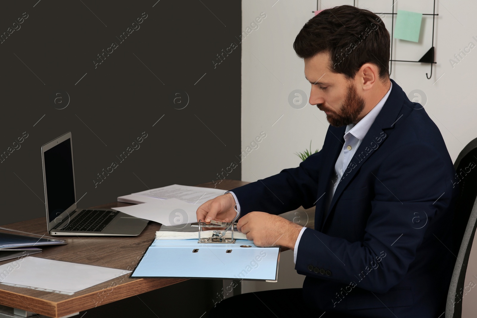 Photo of Businessman with file folder at wooden table in office