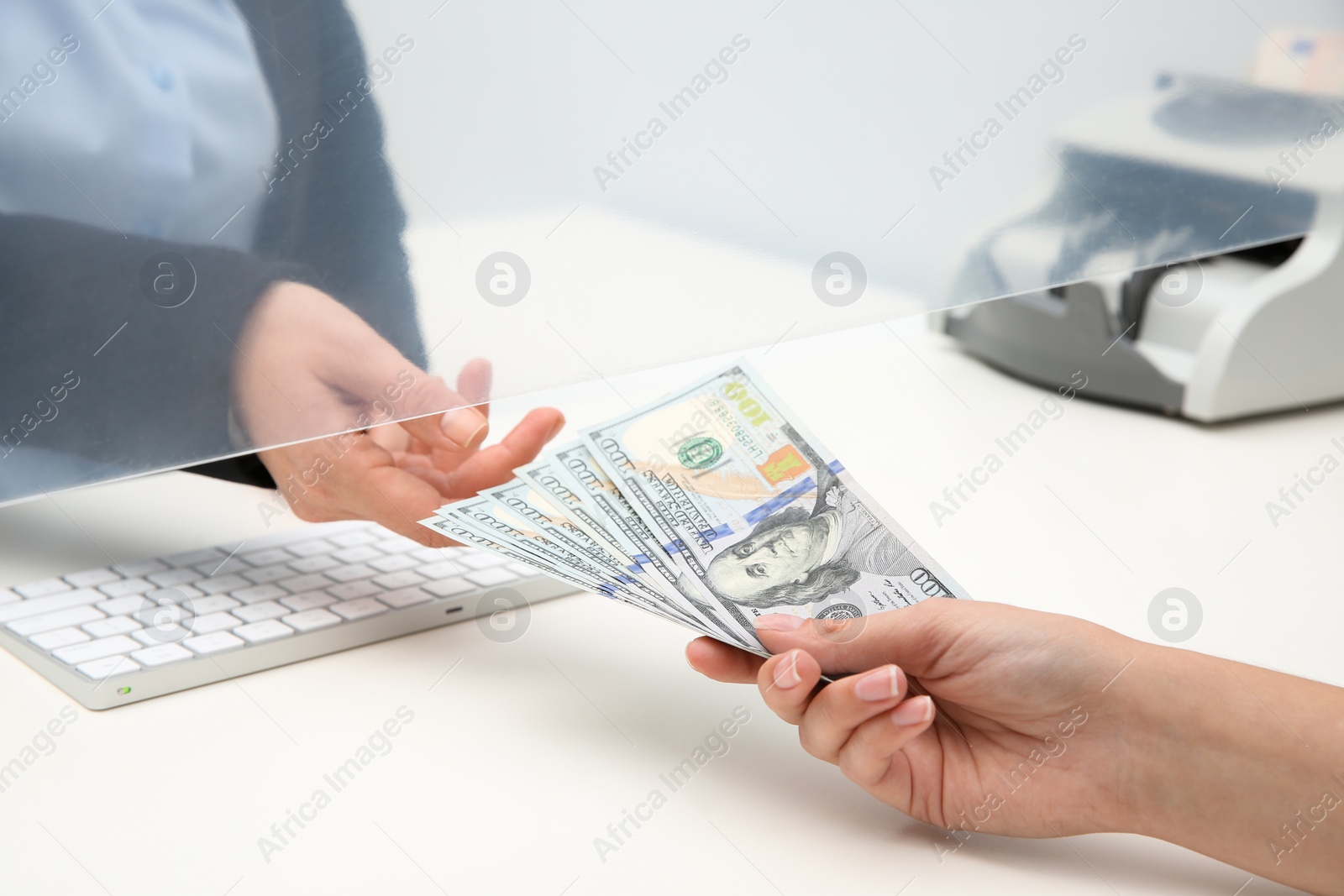 Photo of Woman giving money to teller at cash department window, closeup