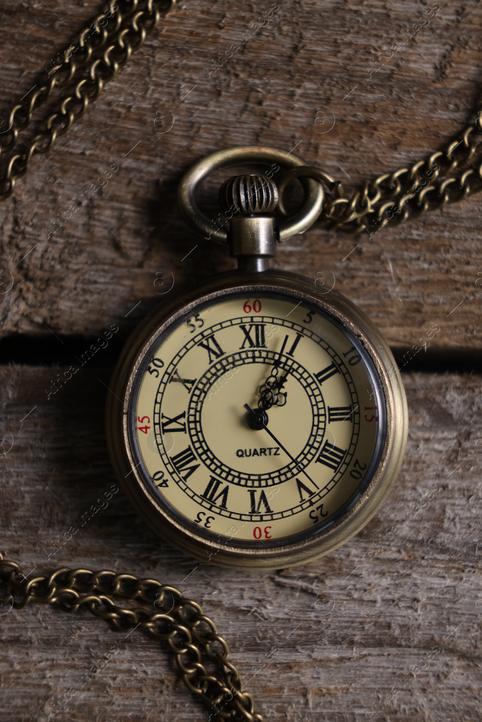 Photo of Pocket clock with chain on wooden table, top view