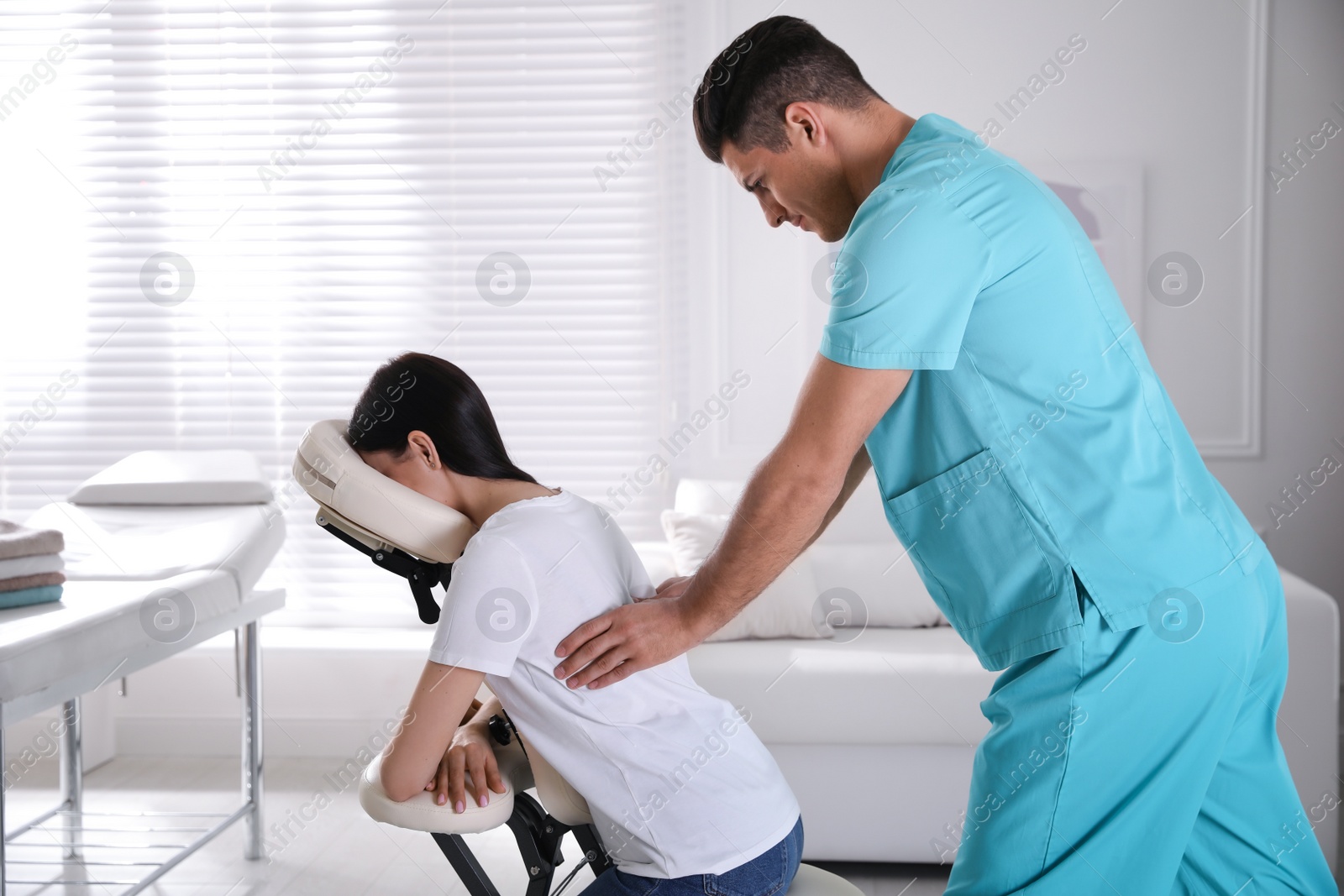 Photo of Woman receiving massage in modern chair indoors