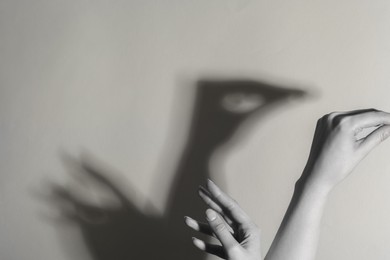 Shadow puppet. Woman making hand gesture like swan on light background, closeup with space for text. Black and white effect
