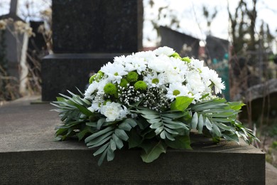 Photo of Funeral wreath of flowers on tombstone in cemetery