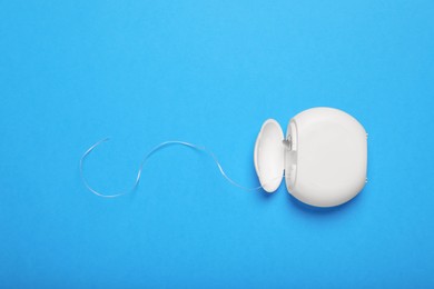 Photo of Container with dental floss on light blue background, top view