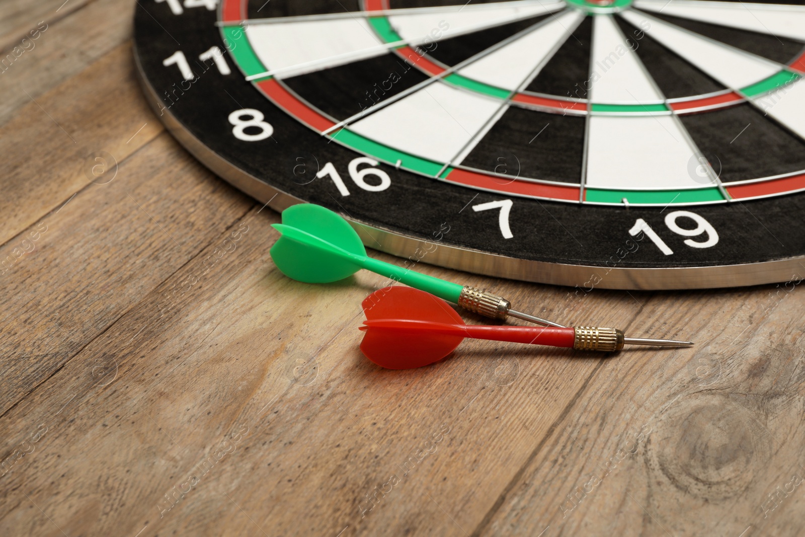 Photo of Dart board with color arrows on wooden background. Space for text