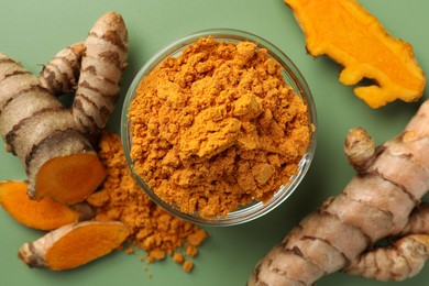 Aromatic turmeric powder and raw roots on green background, flat lay