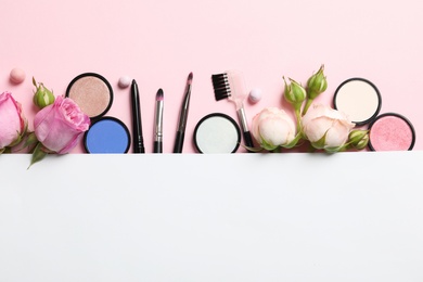 Flat lay composition with card and products for decorative makeup on pastel pink background