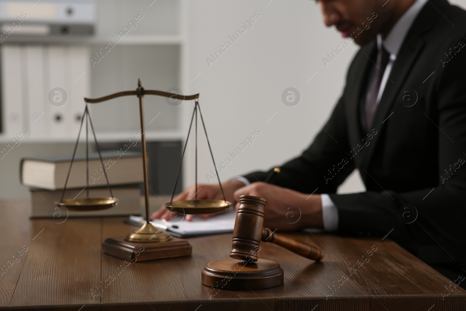 Photo of Law and justice. Closeup of judge working at wooden table in office, focus on gavel