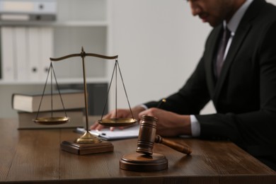 Law and justice. Closeup of judge working at wooden table in office, focus on gavel