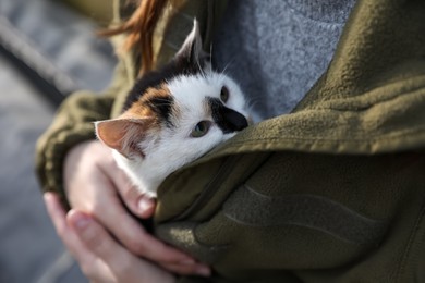 Photo of Soldier in uniform warming little stray cat, closeup