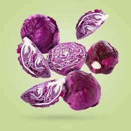 Image of Fresh whole and cut red cabbages falling on pale light green background