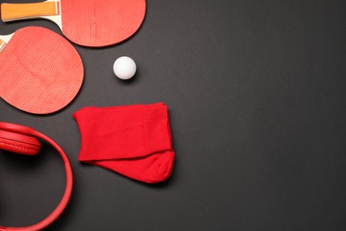 Sports equipment. Ping pong rackets, ball, headphones and socks on black background, flat lay. Space for text