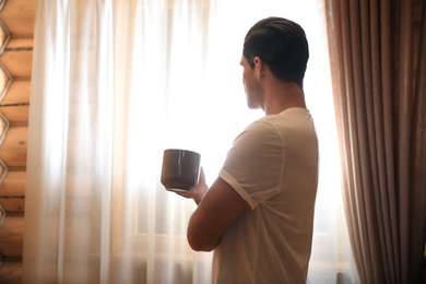 Photo of Man with drink near window indoors. Lazy morning