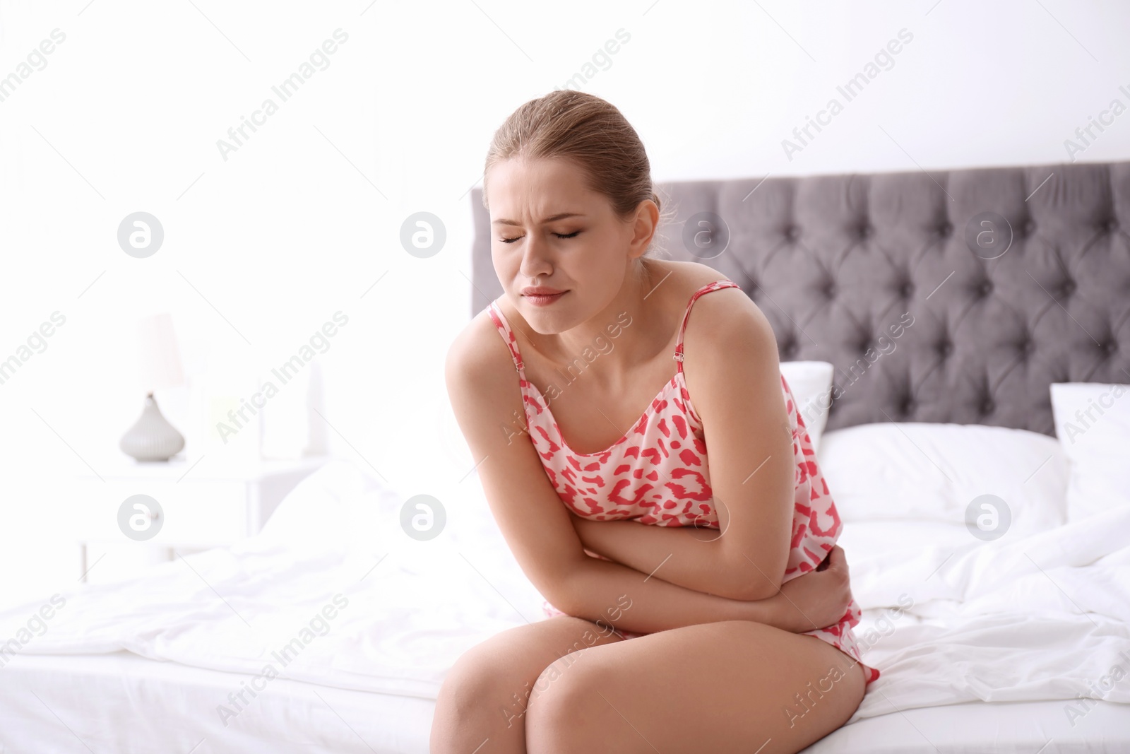 Photo of Young woman suffering from menstrual cramps at home. Gynecology