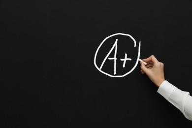 Image of School grade. Teacher encircling letter A and plus symbol with chalk on blackboard