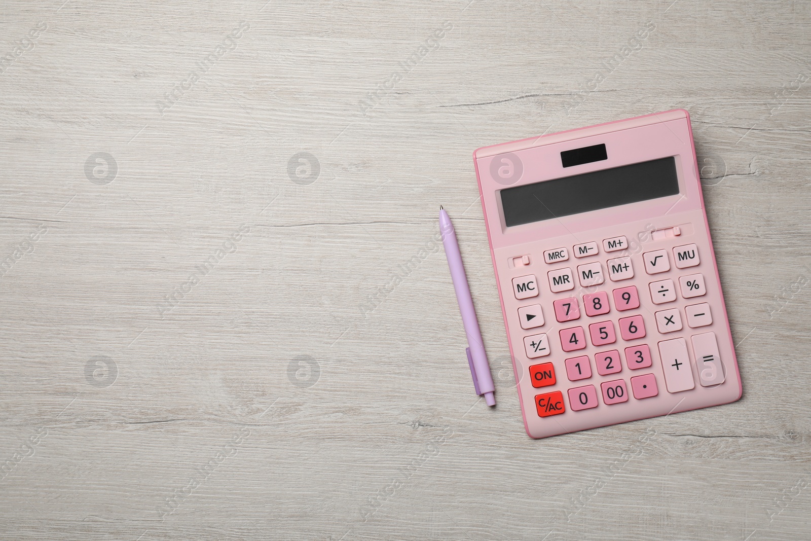 Photo of Calculator and pen on light wooden table, top view. Space for text