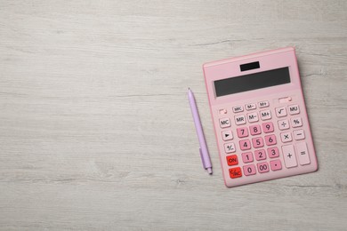 Calculator and pen on light wooden table, top view. Space for text