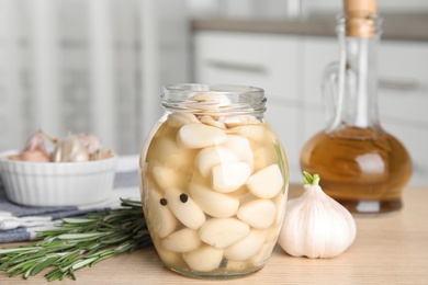Photo of Composition with jar of pickled garlic on wooden table indoors