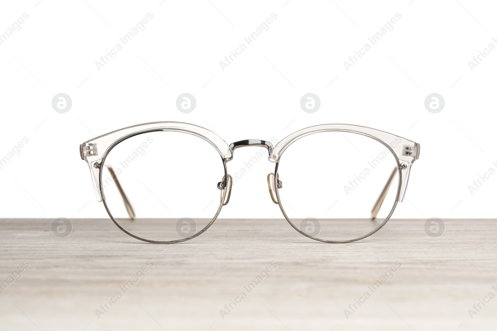 Photo of Stylish glasses on wooden table against white background