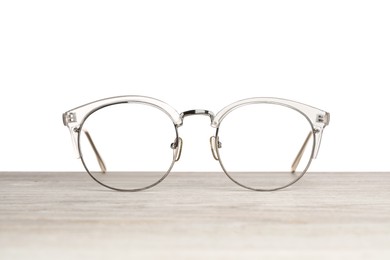 Photo of Stylish glasses on wooden table against white background