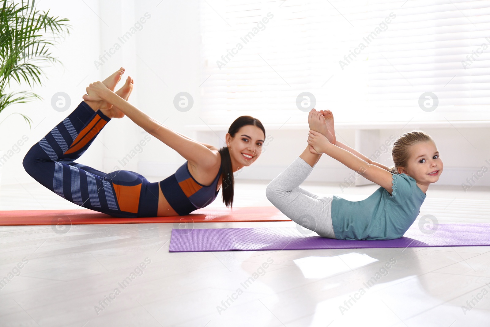 Photo of Woman and daughter doing yoga together at home. Fitness lifestyle