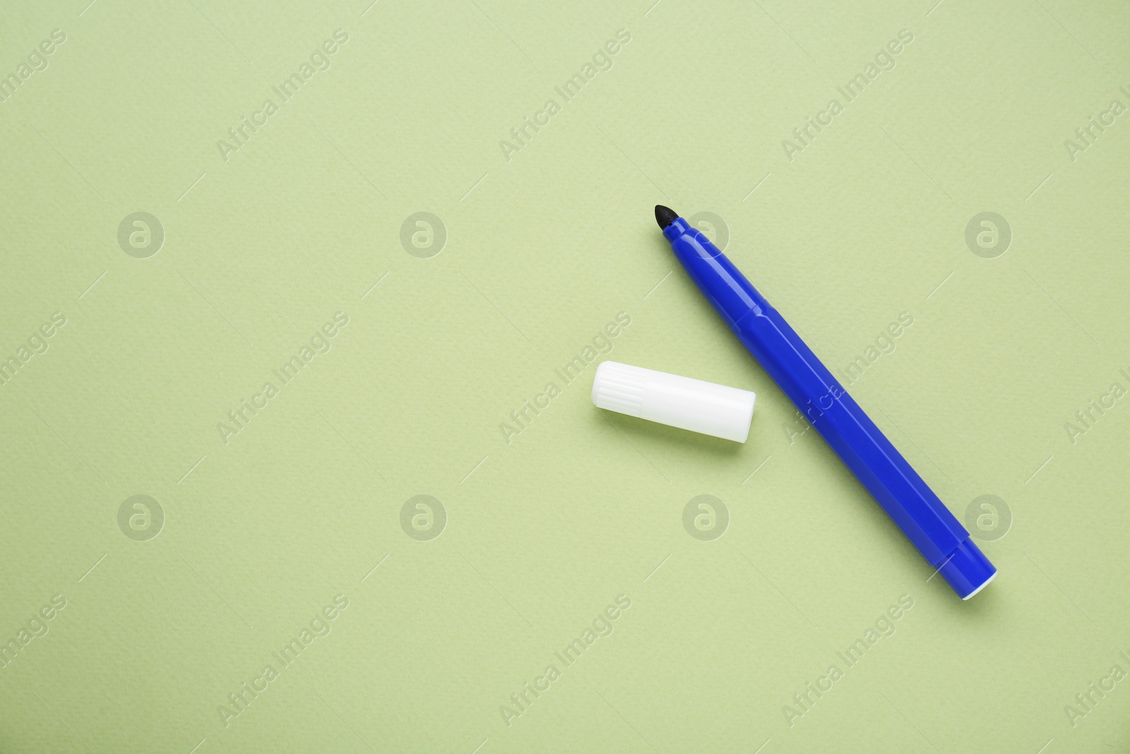 Photo of Blue marker with cap on light green background, flat lay. Space for text