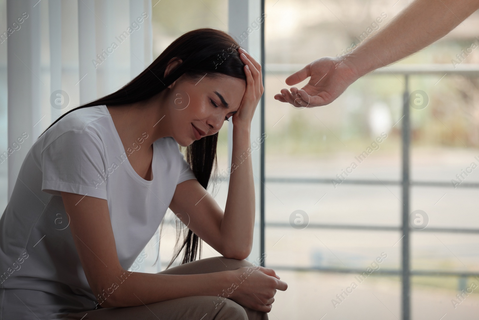 Photo of Man offering hand to depressed woman indoors