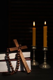Photo of Church candles, Bible, rosary beads and cross on wooden table