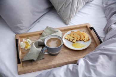 Photo of Aromatic coffee, biscuit and beautiful flower on bed with grey linens indoors