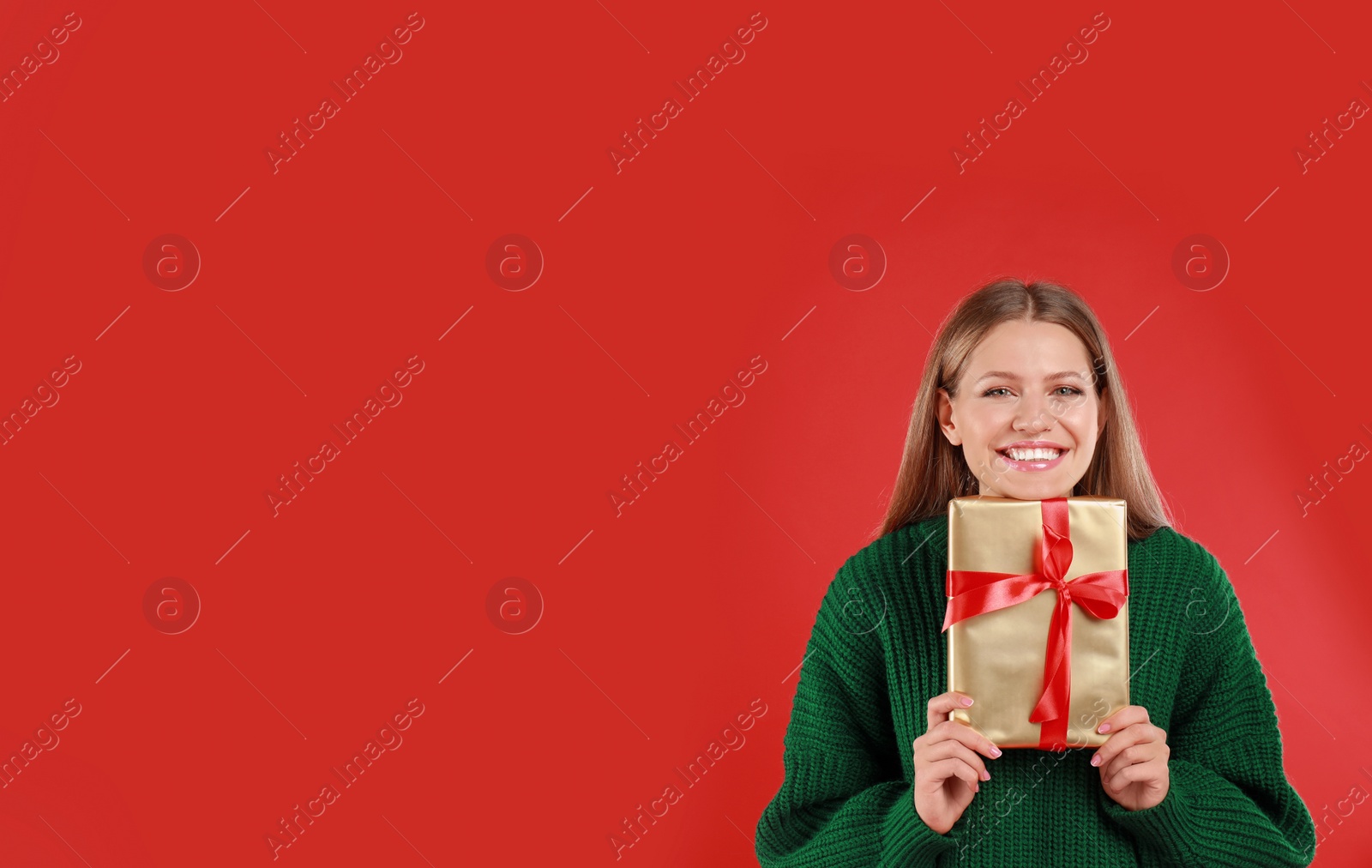 Photo of Happy young woman with Christmas gift on red background. Space for text