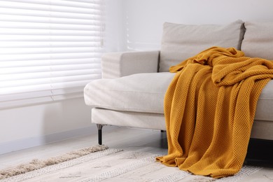 Photo of Cozy orange plaid on sofa in room. Space for text
