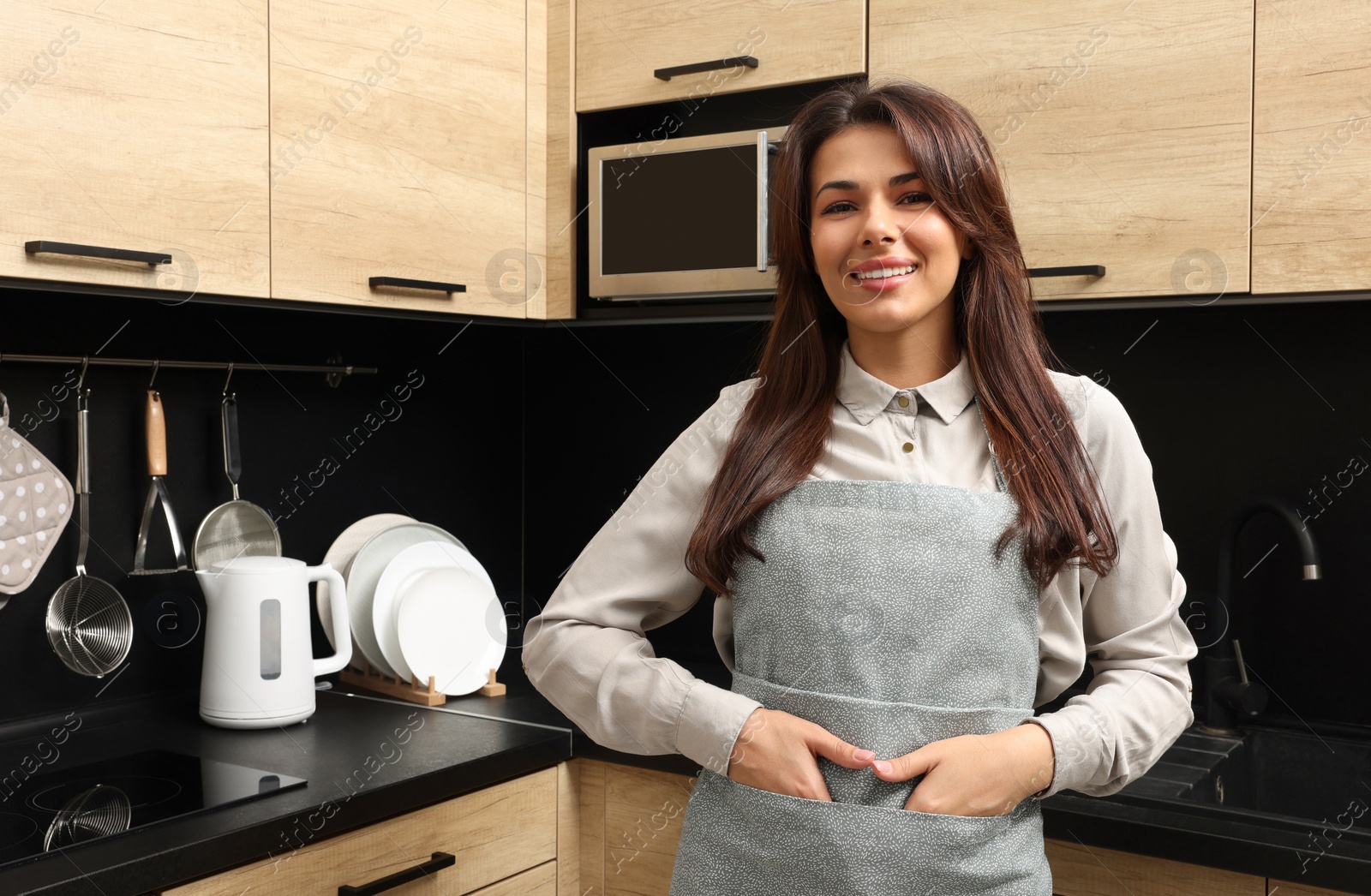 Photo of Young woman wearing green apron in kitchen, space for text