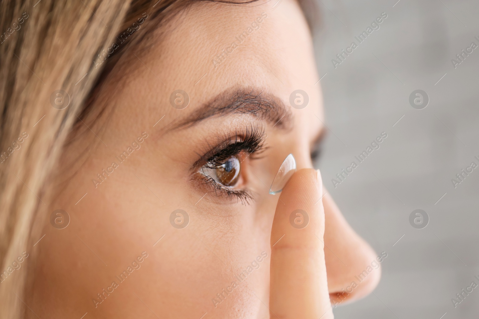 Photo of Young woman putting in contact lens, closeup