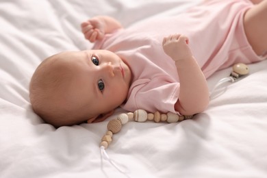 Photo of Cute little baby with toy lying on white sheets