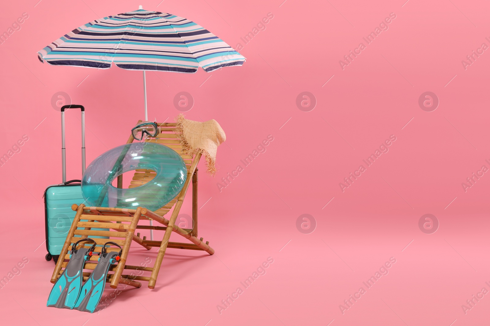 Photo of Deck chair, suitcase and beach accessories on pink background, space for text