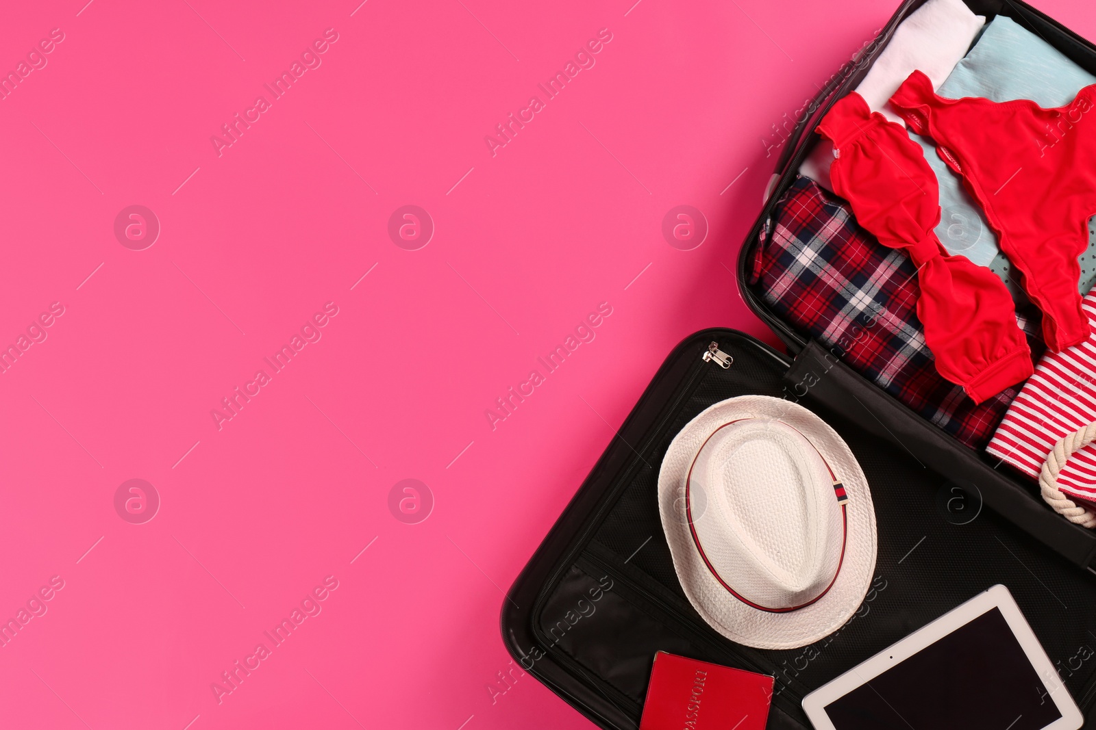 Photo of Open suitcase with traveler's belongings on color background, top view. Space for text