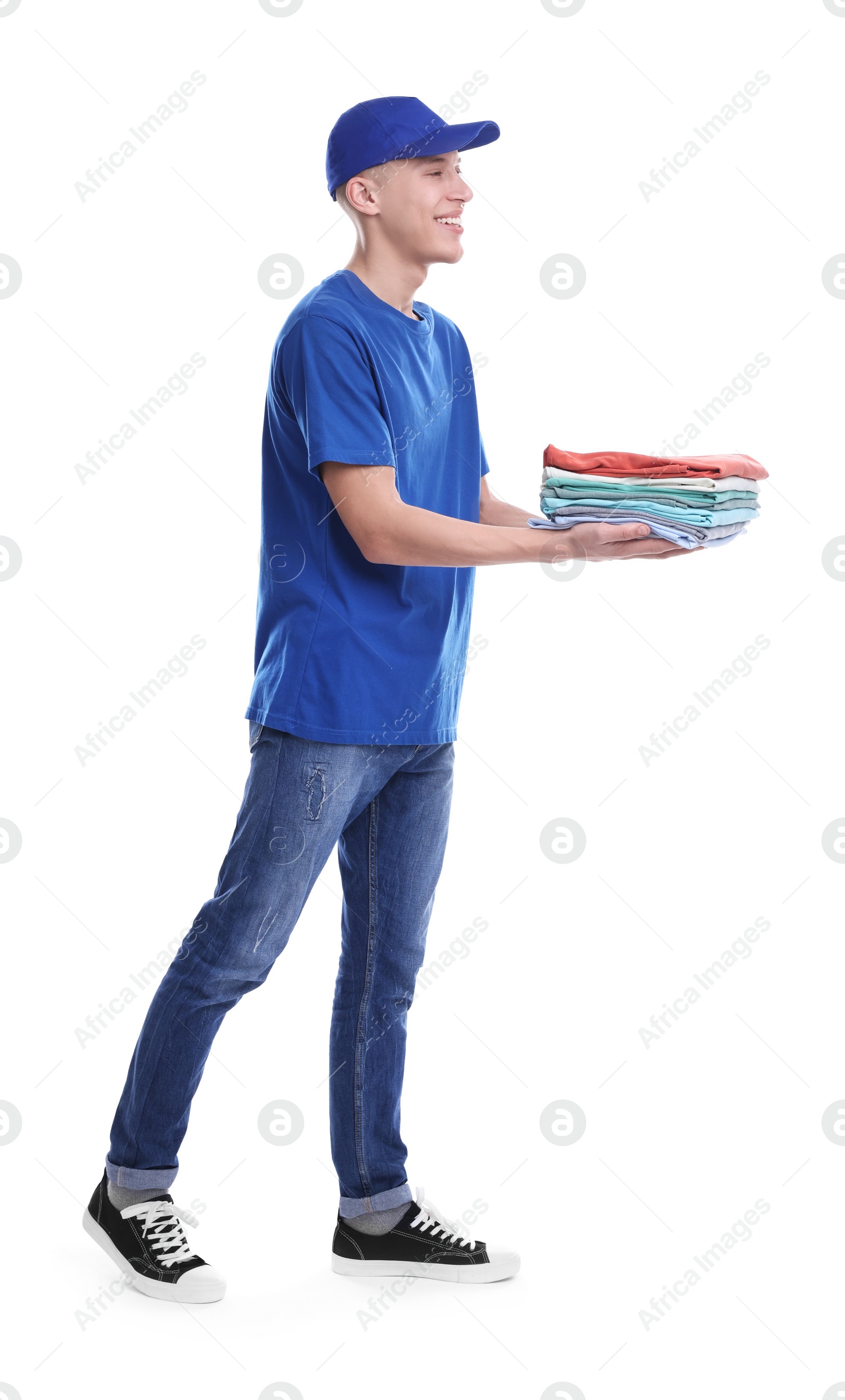 Photo of Dry-cleaning delivery. Happy courier holding folded clothes on white background