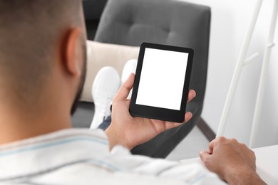 Photo of Man using e-book reader indoors, closeup view