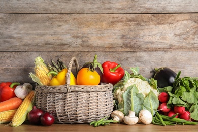 Assortment of fresh vegetables on table against wooden background. Space for text