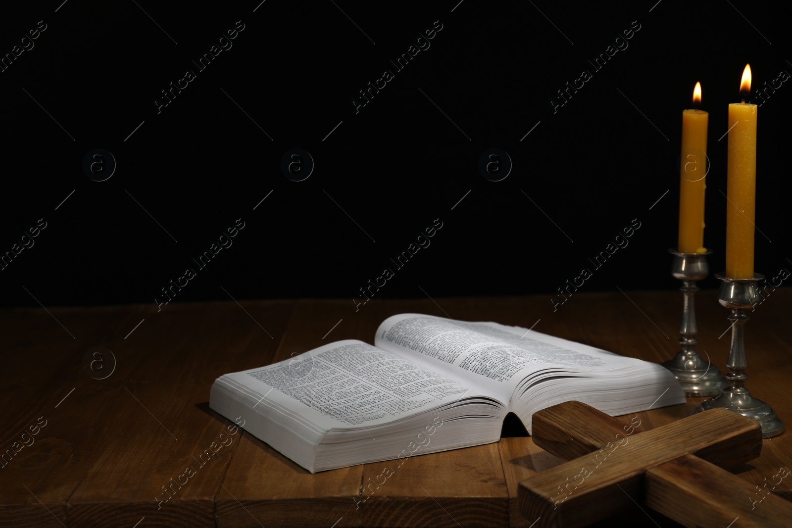 Photo of Bible, cross and church candles on wooden table, space for text