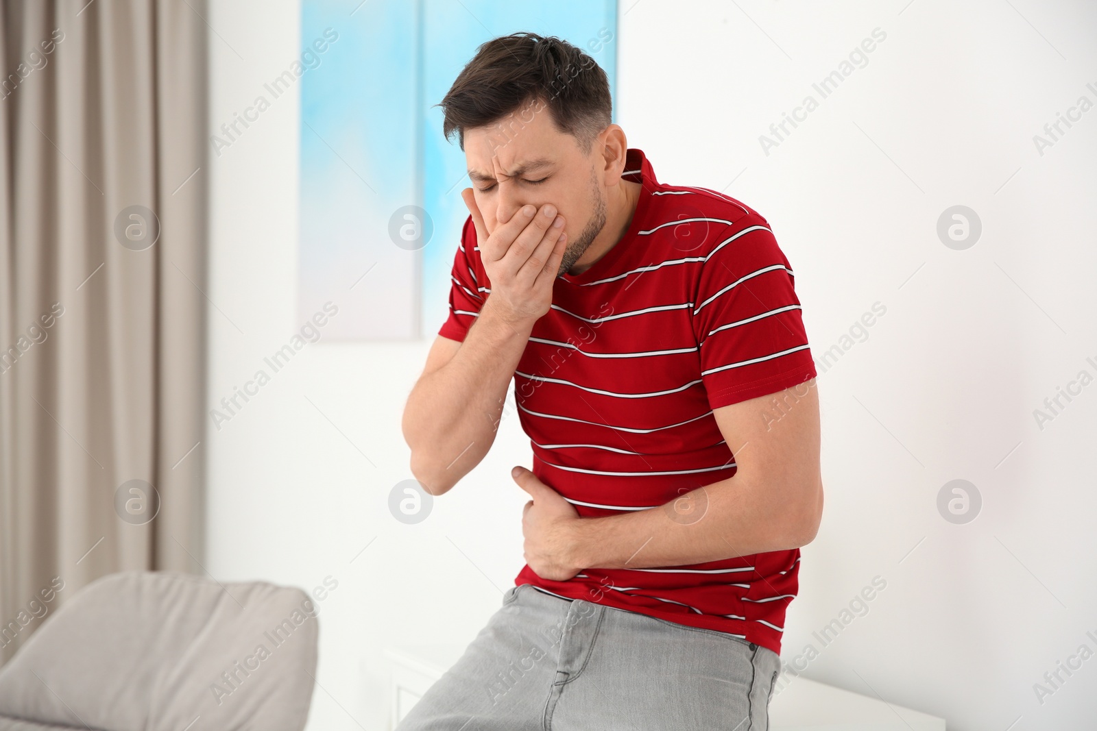 Photo of Young man having nausea at home. Space for text