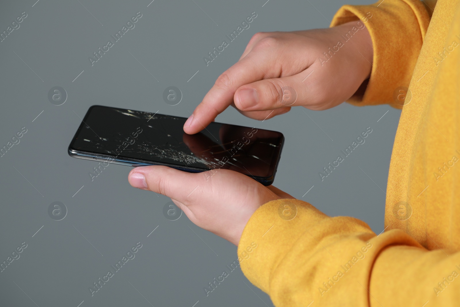 Photo of Man holding damaged smartphone on light grey background, closeup. Device repairing