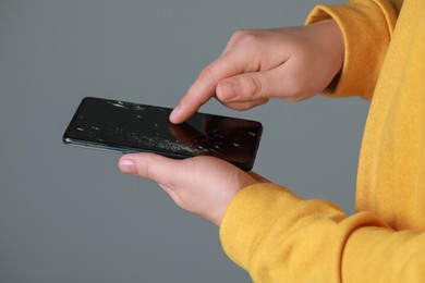 Photo of Man holding damaged smartphone on light grey background, closeup. Device repairing