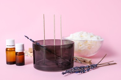 Composition with ingredients for homemade candle on pink background