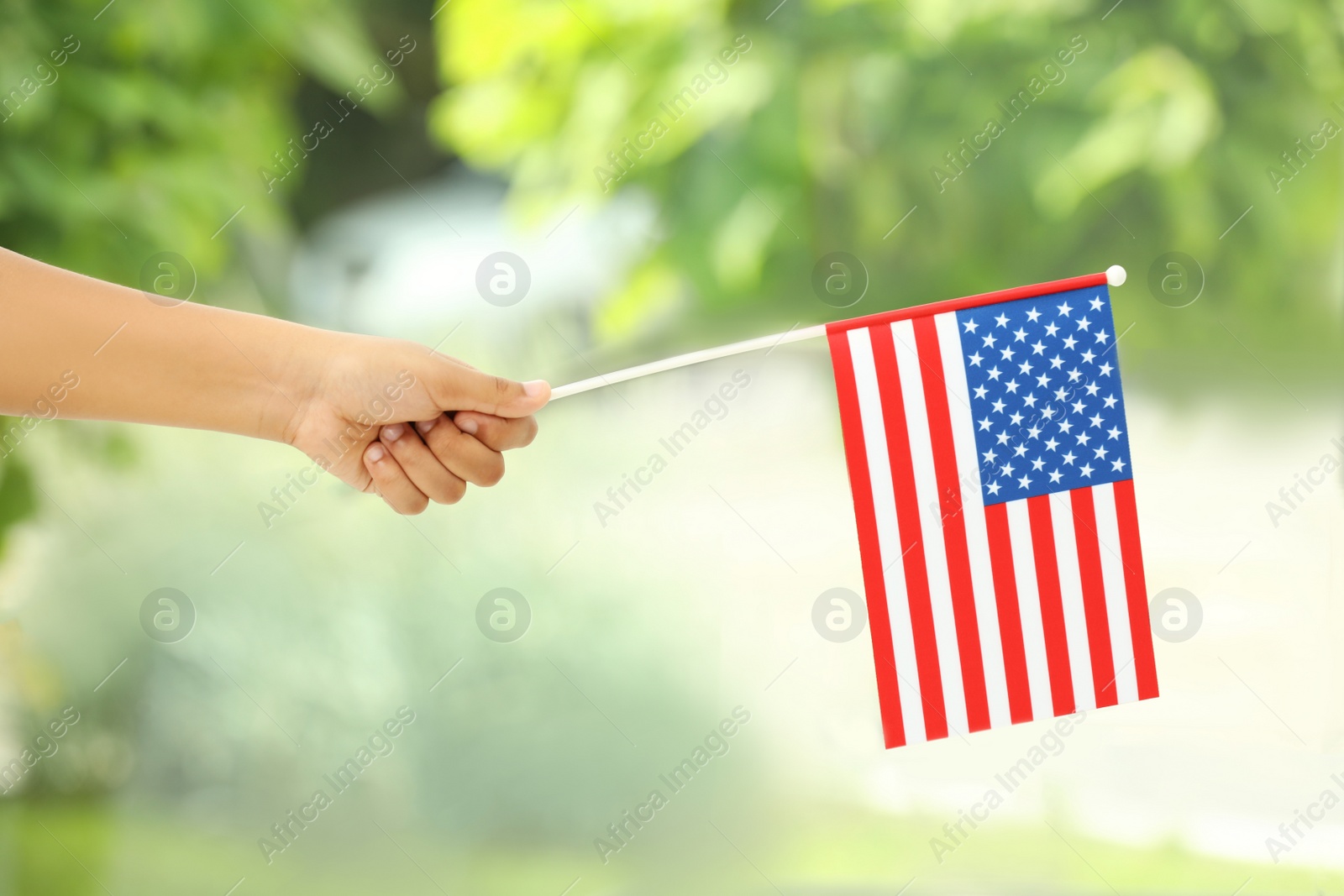 Photo of African-American child holding national flag on blurred background, closeup