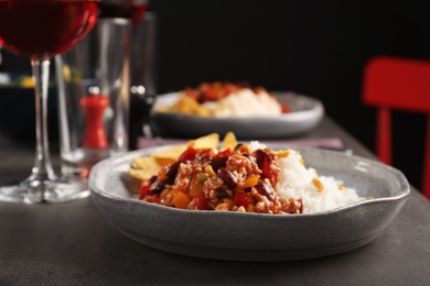 Photo of Tasty chili con carne served with rice on gray table. Dinner in restaurant