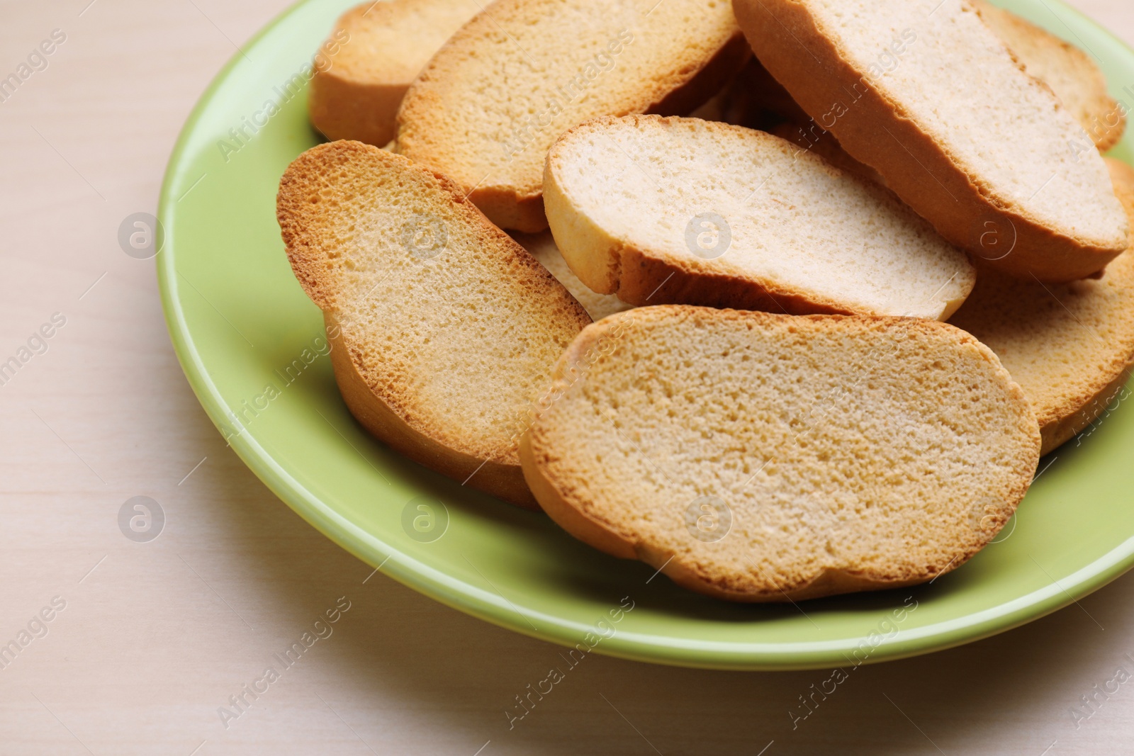 Photo of Plate of hard chuck crackers on wooden table, closeup